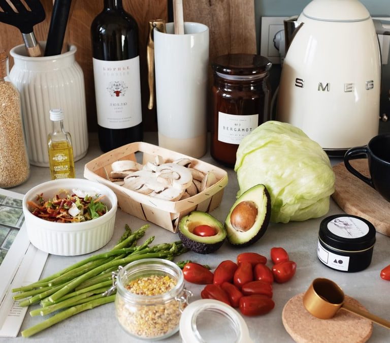 Assorted healthy food and vegetables set locating on gray countertop next to various utensils and appliances during cooking in stylish kitchen