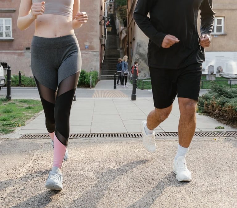 Fit couple jogging together on an urban sidewalk in sportswear.