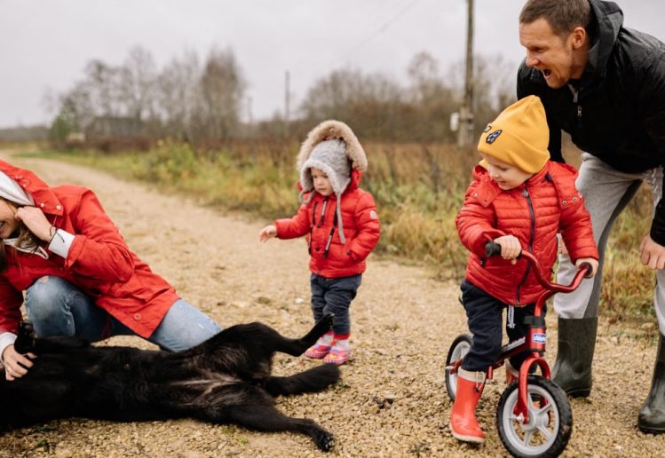 Happy family enjoying quality time outdoors with kids and dog in countryside.