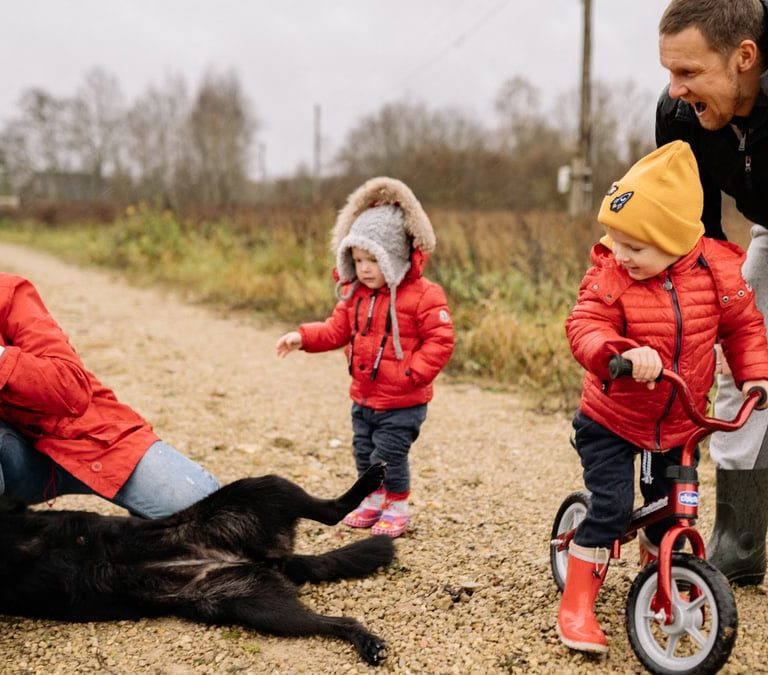 Happy family enjoying quality time outdoors with kids and dog in countryside.